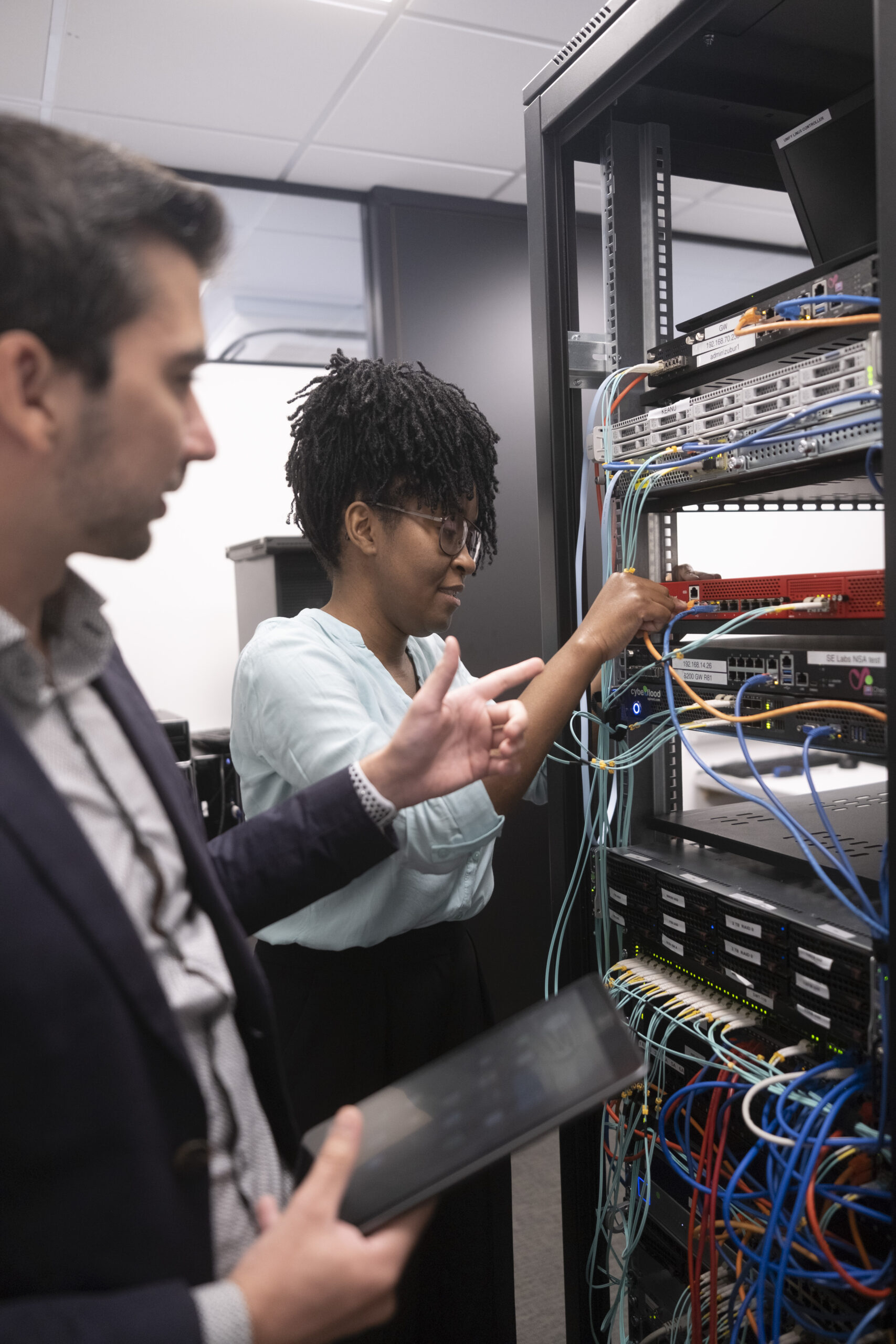 Two SE Labs employees configure a network device in SE Labs' dedicated hardware testing facility